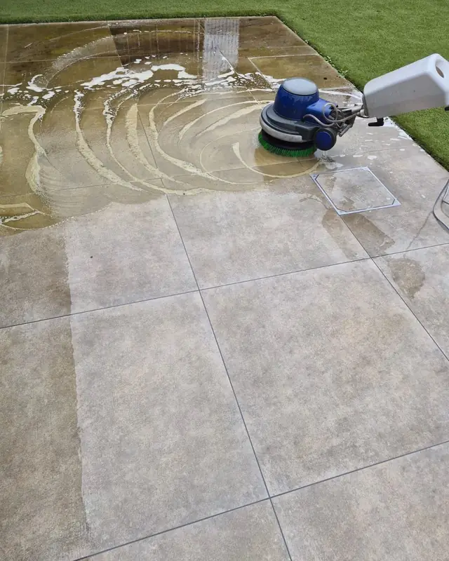 Borstelmachine van Clean Floors in een laagje water op terrastegels