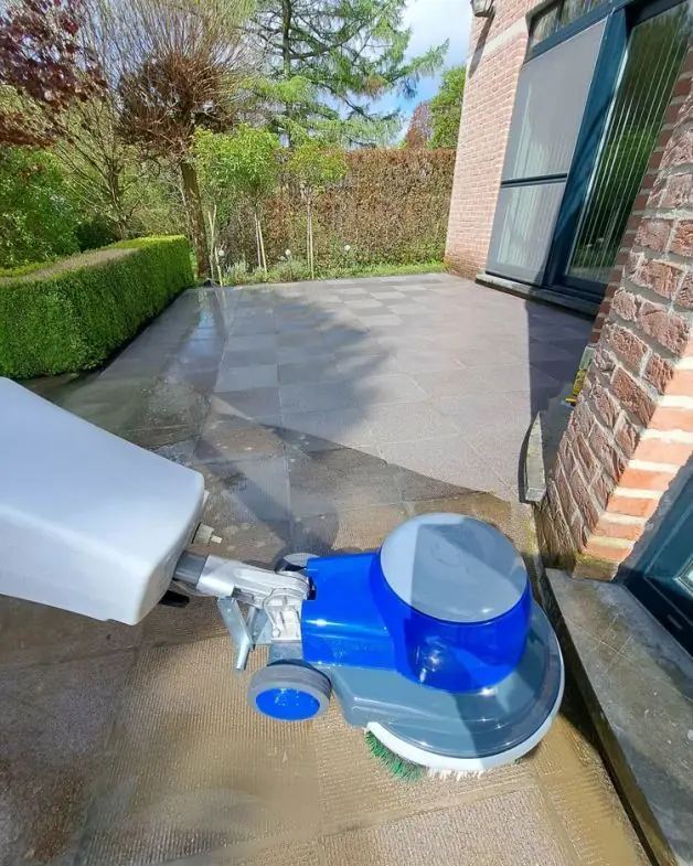 Borstelmachine van Clean Floors op een terras in grote tegels naast de gevel