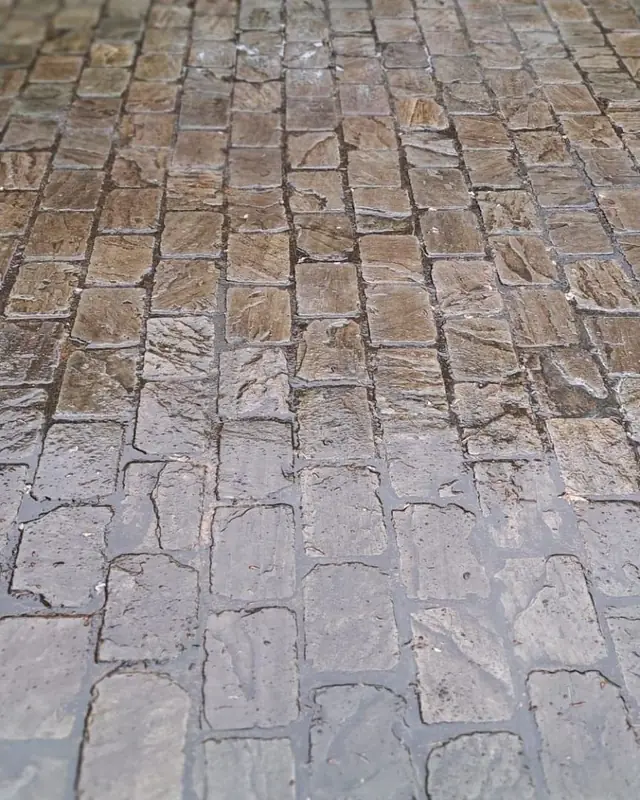 Kasseienterras tijdens de reiniging, nog nat en bruin