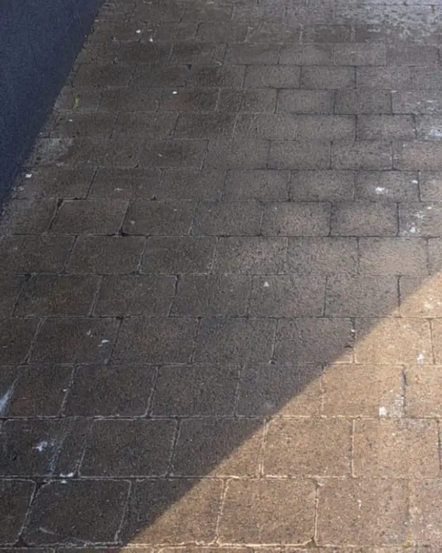 Natte, donkere klinkers langs een witte gevel