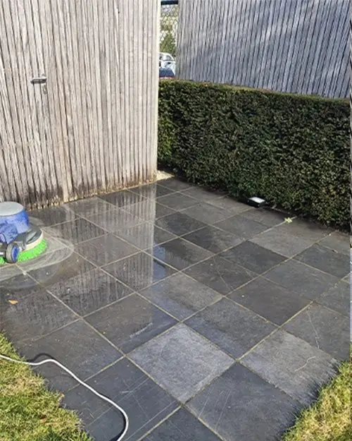 Grijze terrastegels met vuil en groene randen