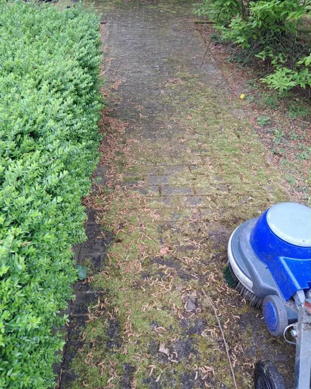 Vuil tuinpad met de borstelmachine aan het begin